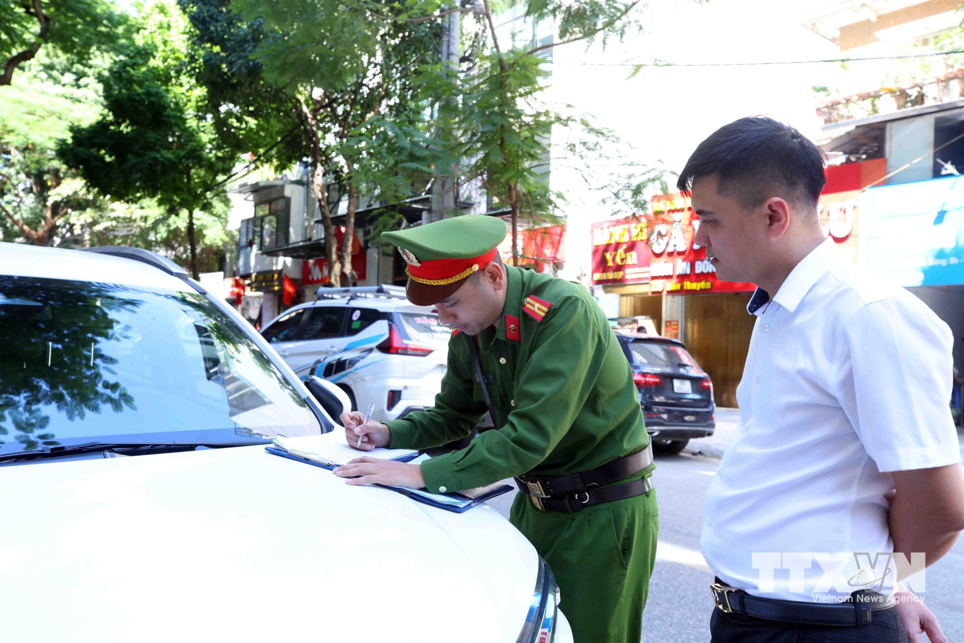 Thông qua hệ thống camera an ninh phát hiện hành vi vi phạm dừng đỗ xe sai quy định, Tổ công tác Công an phường Hai Bà Trưng đã nhanh chóng có mặt tại hiện trường để tiến hành xử phạt chủ phương tiện theo quy định pháp luật. (Ảnh: Phạm Kiên/TTXVN)